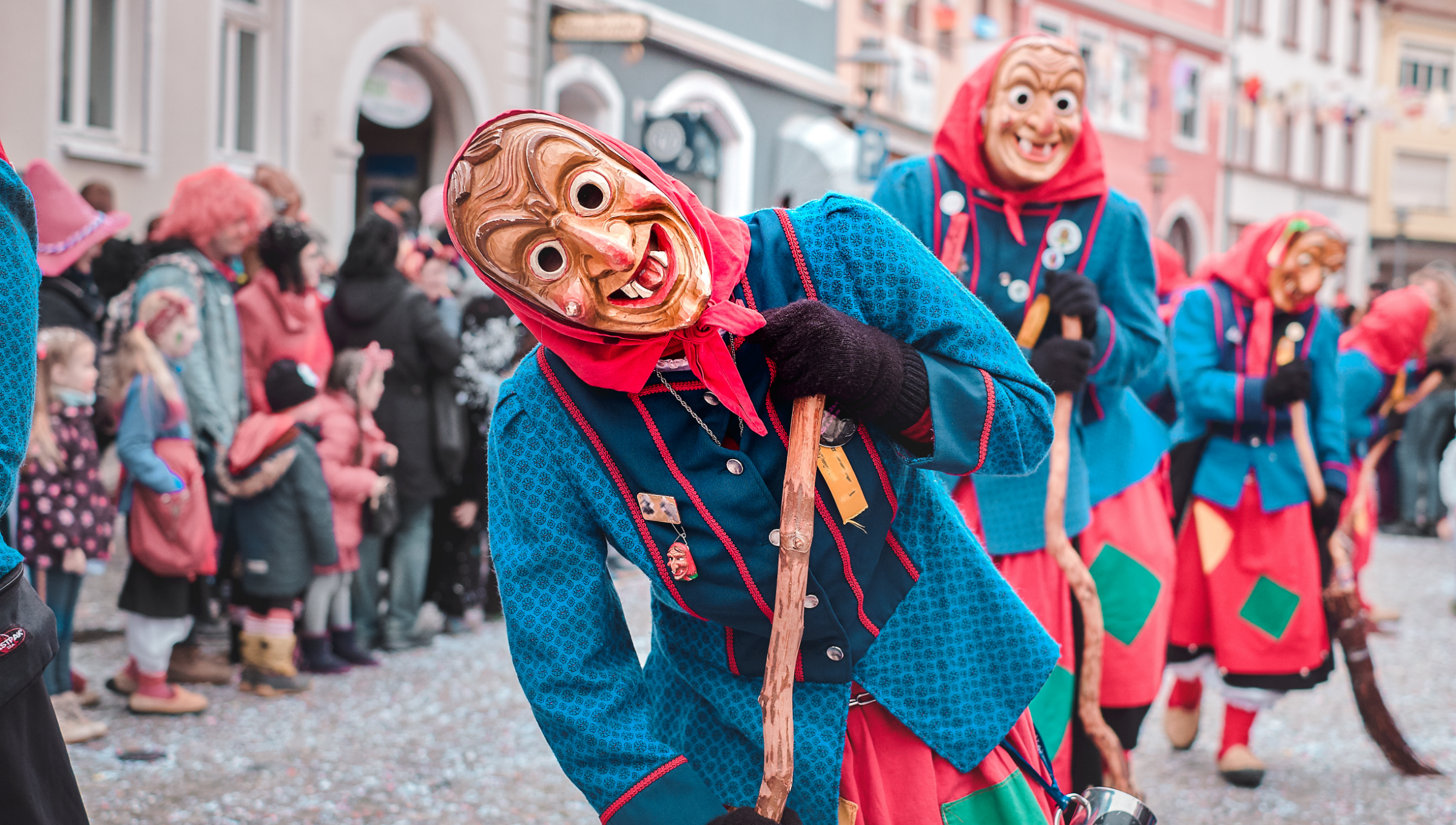 
Verkleidete Faschingshexen mit hölzernen Masken beim Straßenumzug.