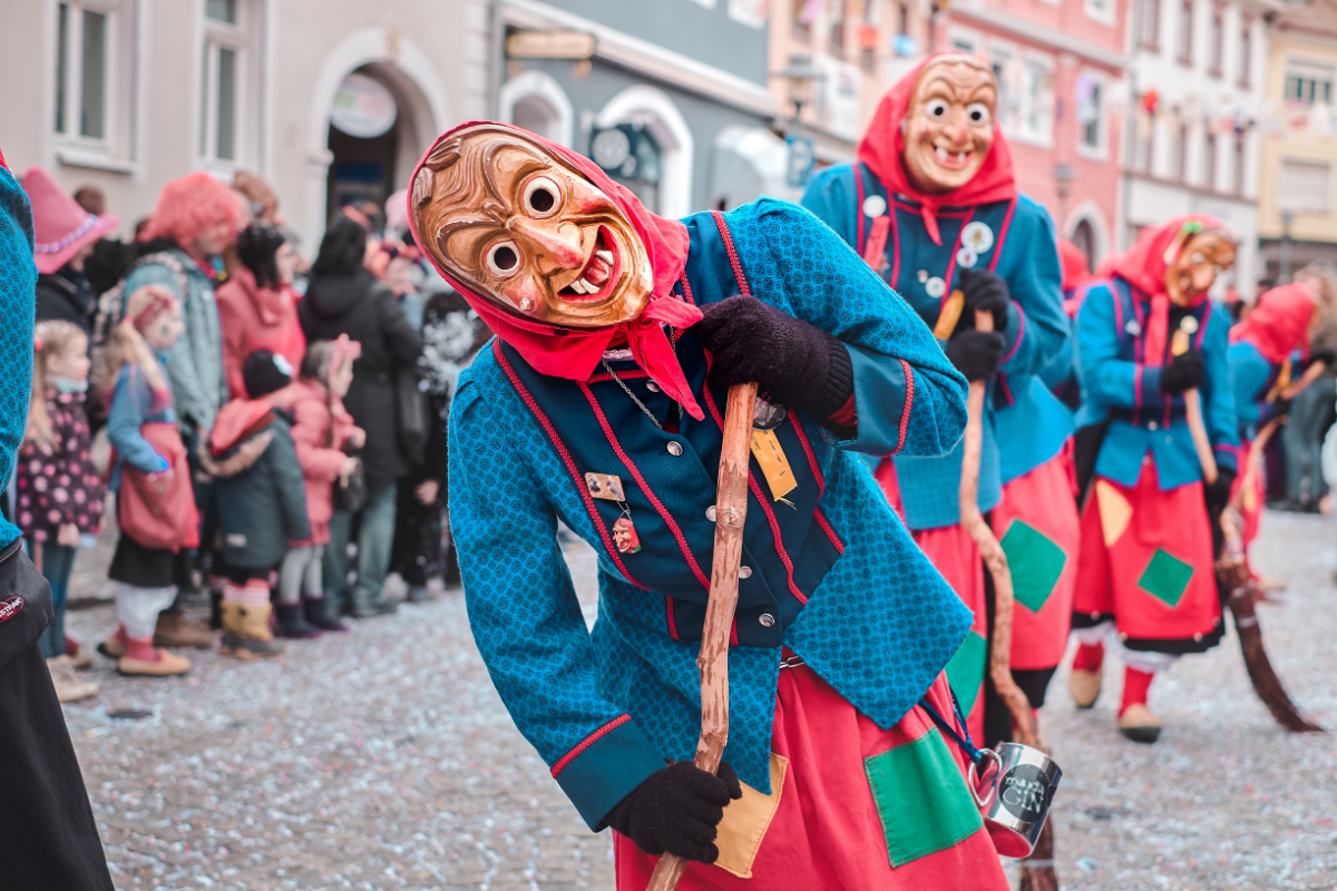 
Verkleidete Faschingshexen mit hölzernen Masken beim Straßenumzug.