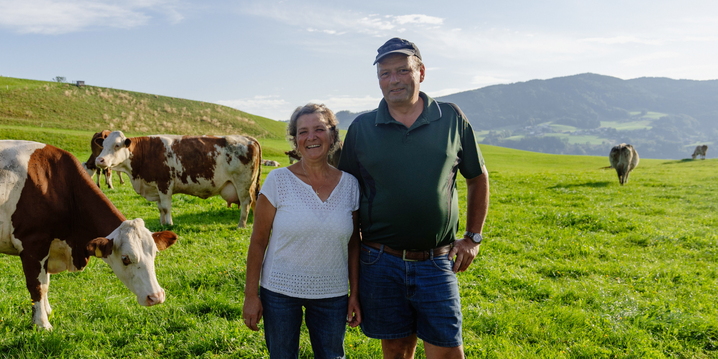 Naturland-Landwirte Herr und Frau Widlroither stehen mit ihren Kühen auf einer Wiese.