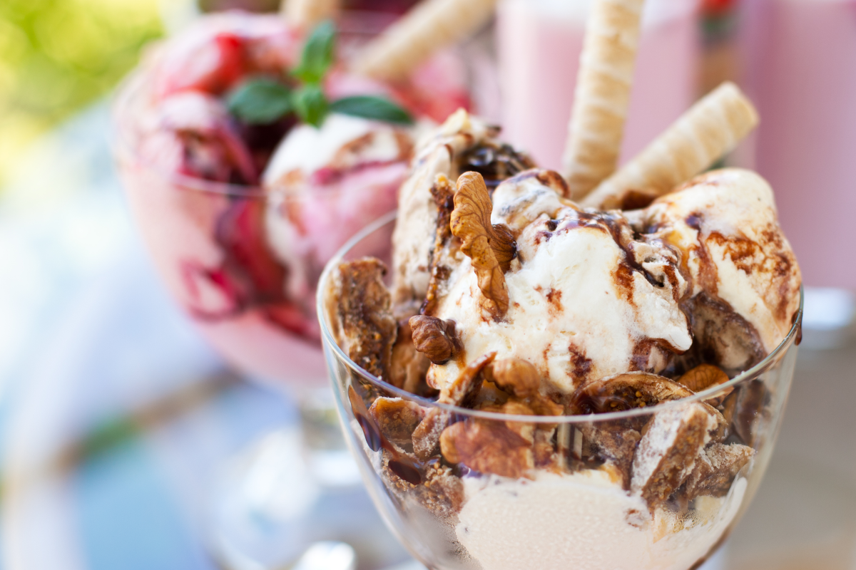 
Eisbecher mit Vanilleeis, Schokoladensauce, Nüssen und Waffelröllchen.